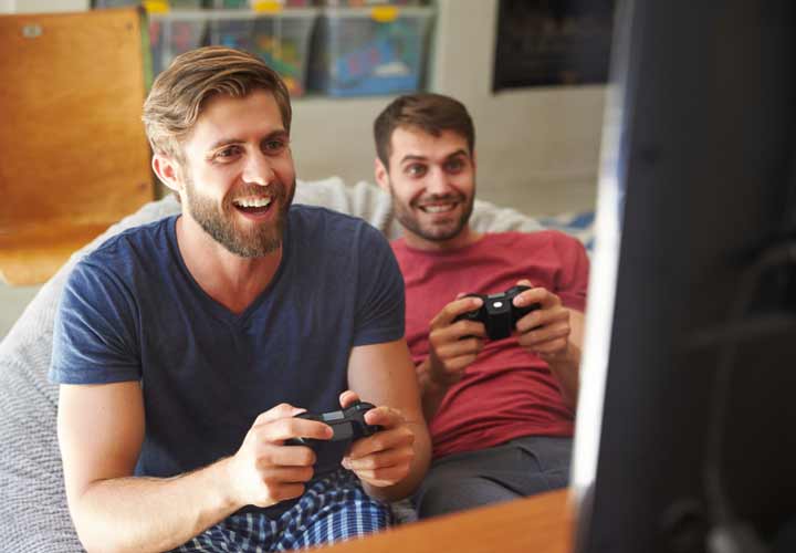 Two Male Friends In Pajamas Playing Video Game Together